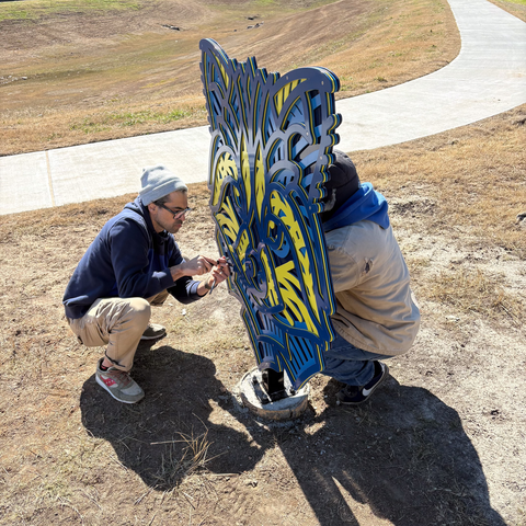 two people putting the finishing touches on a raccoon relief sculpture