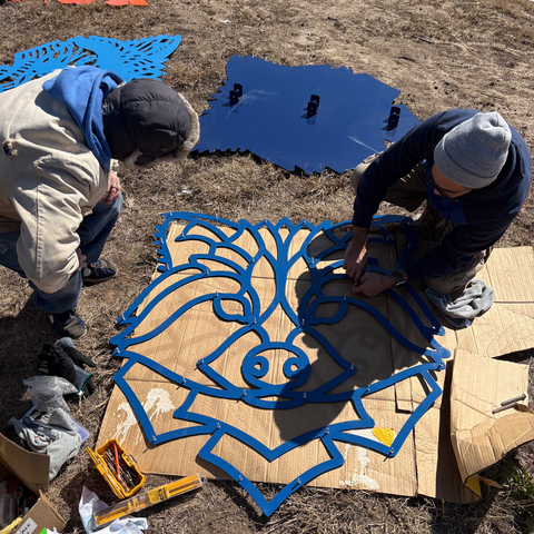 two people assembling a raccoon relief sculpture